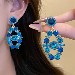 Detail shot of vintage royal blue rhinestone earrings with a teardrop crystal center