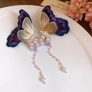 Detailed view of purple embroidered butterfly earrings with elegant pearl tassels