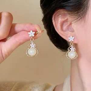Primo piano dettagliato di eleganti orecchini a fiore bianco e zucca indossati sull'orecchio