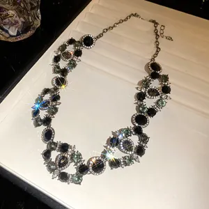 Detailed view of a vintage palace style necklace with black and green circular rhinestones