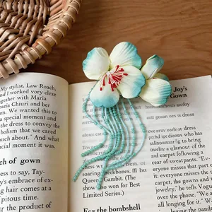 Close-up of handmade fabric flower hair clip with mint green glass bead tassels