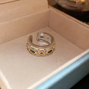 Vista dettagliata di un anello aperto vintage con zirconi verdi e rossi operati