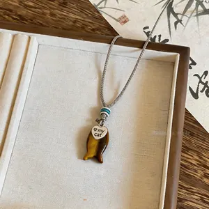 Primo piano della collana intrecciata a mano con ciondolo a pesce in occhio di tigre