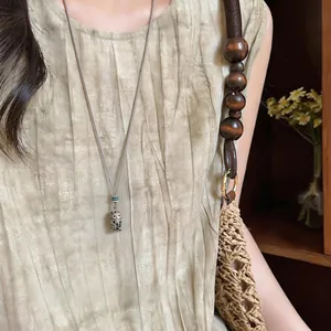 Dettaglio della collana con ciondolo a forma di gufo vintage su abito in lino stile resort