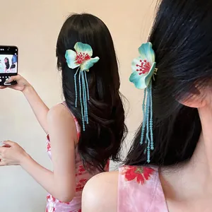 Detailed macro view of handmade fabric flower hair clip with dangling glass beads.