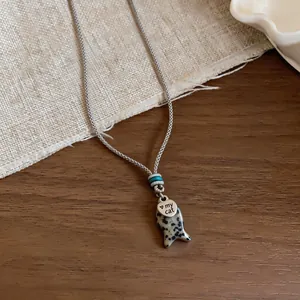 Dettaglio della collana in corda fatta a mano con ciondolo a pesce e 'my cat'.