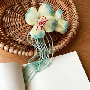 Detailed view of fabric flower hair clip with green beaded tassels on woven basket
