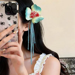 Close-up of elegant fabric flower hair clip with long light blue beaded glass tassels