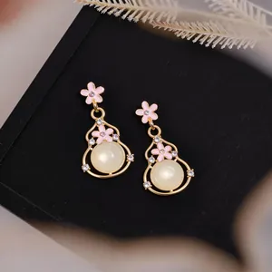 Primo piano di eleganti orecchini a zucca con fiori rosa e perle di resina dettagli.