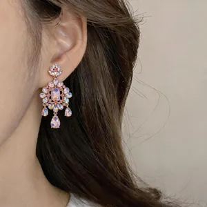 Detailed close-up of flower-shaped earrings with pink rhinestones and teardrop crystals