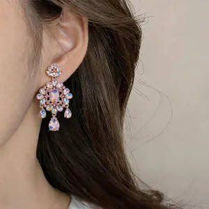 Close-up of iridescent rhinestones and floral design on a dangling earring worn by model