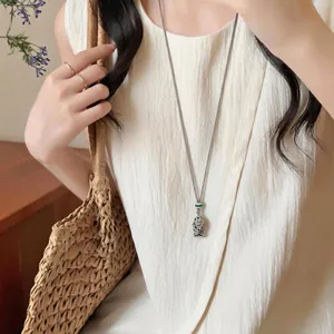 Collana con ciondolo a forma di pesce fatta a mano abbinata a un abito estivo e borsa di paglia