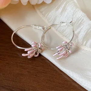 Macro detail view of elegant silver hoop earrings with pink enamel flower charms and zircons