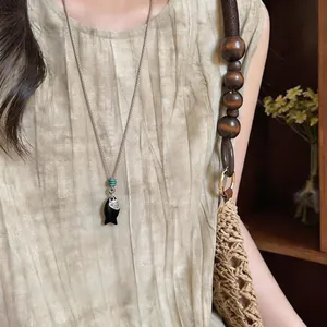 Primo piano della collana con ciondolo a forma di pesce su abito a pieghe