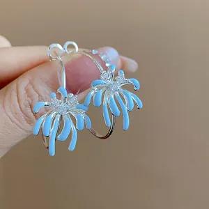 Detailed macro view of blue oil-drop flower hoop earrings with sparkling zircon accents