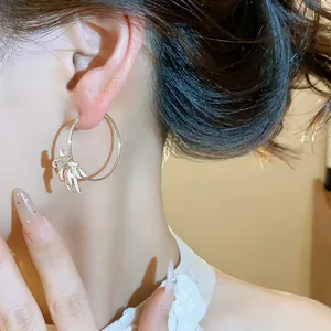 Close-up of elegant zircon flower hoop earring on ear, showing delicate enamel petals.