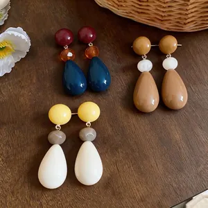 Stylish resin teardrop earrings in vibrant dopamine colors shown on a textured wood surface