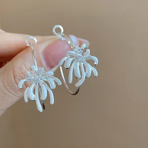 Detailed view of silver hoop earrings with white drip oil floral and zircon accents