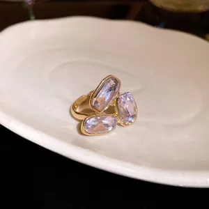 Vista dettagliata di un anello aperto dorato con tre scintillanti cristalli ovali viola chiaro