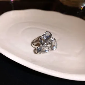 Vista dettagliata di un anello aperto in argento con tre gemme chiare brillanti