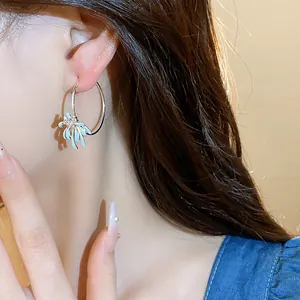 Close-up of elegant silver hoop earrings with a light blue enamel flower charm detail