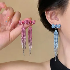 Detail view of sparkling rhinestone bow tassel earrings with a long gradient drop design.