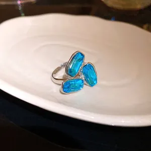 Primo piano di un anello regolabile in argento con tre cristalli sfaccettati blu.
