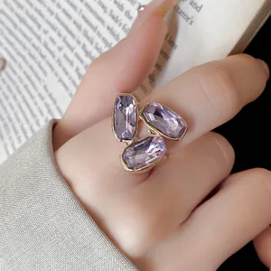 Dettaglio di un anello regolabile dorato con tre cristalli ovali di colore viola