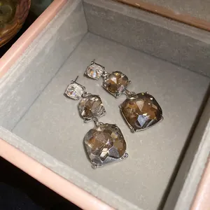 Close-up of elegant three-tier square gemstone drop earrings inside a premium jewelry box gift