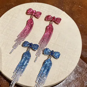Detailed view of pink and blue rhinestone bow earrings with long sparkling tassels