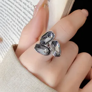 Primo piano di un anello d'argento con tre pietre grigie rettangolari sul dito.
