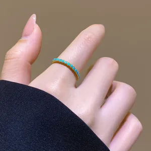 Nahaufnahme eines 18 Karat vergoldeten Rings mit türkisfarbenen Steinen am Finger.