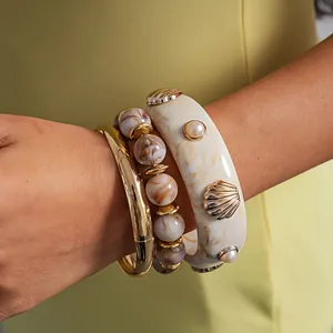 Close-up detail of three-piece retro resin shell and beaded bracelet set on a wrist