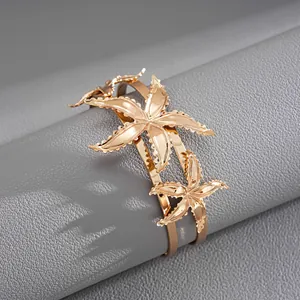 Macro view of a luxury golden cuff bracelet showcasing intricate double starfish designs.