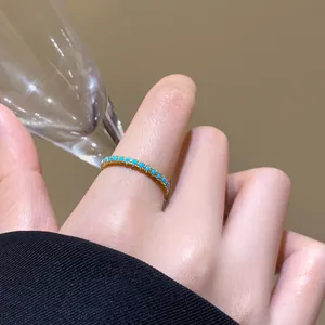 Nahaufnahme eines eleganten vergoldeten Rings mit türkisen Steinen an einer Hand