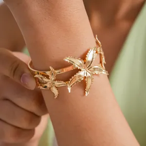 Detailed close-up of a stylish gold metallic starfish bangle worn on a model's arm