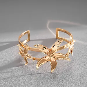 Detail view of a gold-toned cuff bracelet with intricate starfish-shaped designs