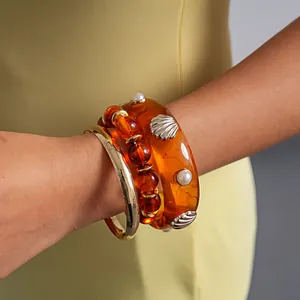Detail view of a vintage 3pcs amber resin and gold shell bracelet set on a model wrist