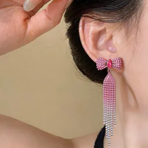 Close-up detail of exquisite pink rhinestone bow tassel earrings on a model's ear