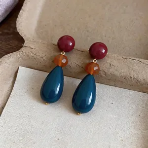 Macro view of colorful resin waterdrop earrings with burgundy and teal beads