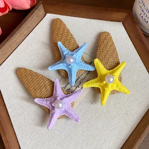 Detailed macro view showing three colorful bohemian starfish hair clips with pearl accents.