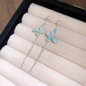 Dettaglio di orecchini a farfalla blu con nappe d'argento e decorazioni in cristallo