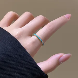 Detaillierte Ansicht eines eleganten 18k vergoldeten Zirkonrings mit türkisen Steinen am Finger.