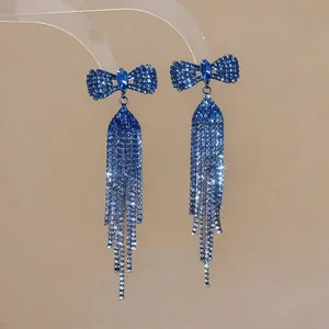 Macro shot of elegant blue rhinestone bow-knot earrings featuring long shimmering tassels