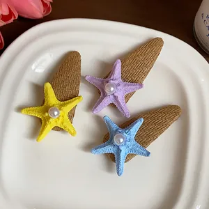 Detailed view of three colorful bohemian starfish hair clips with pearls on a white plate