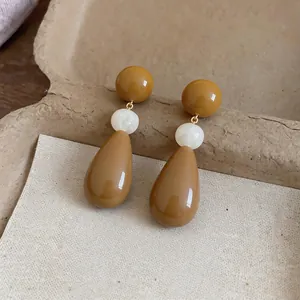 Detailed view of mustard yellow resin drop earrings with marble-textured beads
