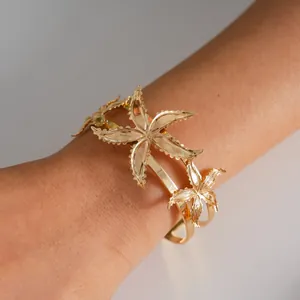 Close-up detail of a gold-toned star-shaped metal cuff bracelet worn on a woman's wrist