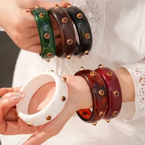 Eleganti bracciali rigidi vintage in resina con trama marmorizzata e borchie dorate decorative