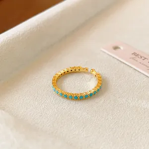 Nahaufnahme eines 18k vergoldeten offenen Rings mit türkisfarbenen Zirkonen