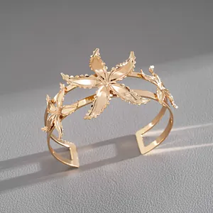 Detailed macro view of an elegant gold-toned starfish motif cuff bracelet on gray texture